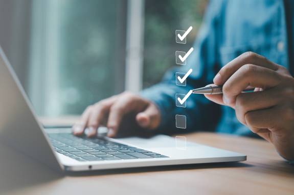 Mann am Laptop hackt Checkliste in der Luft ab