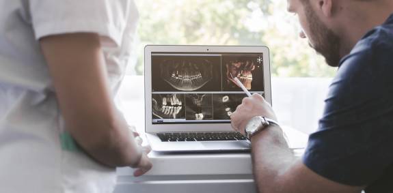 Zahnarzt zeigt Röntgenbilder auf dem Laptop