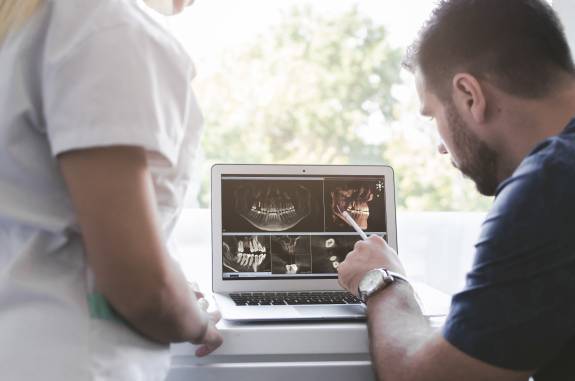 Zahnarzt zeigt Röntgenbilder auf dem Laptop