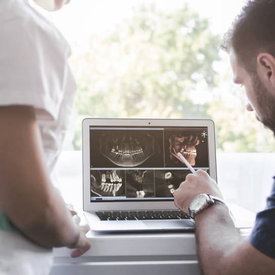 Zahnarzt zeigt Röntgenbilder auf dem Laptop