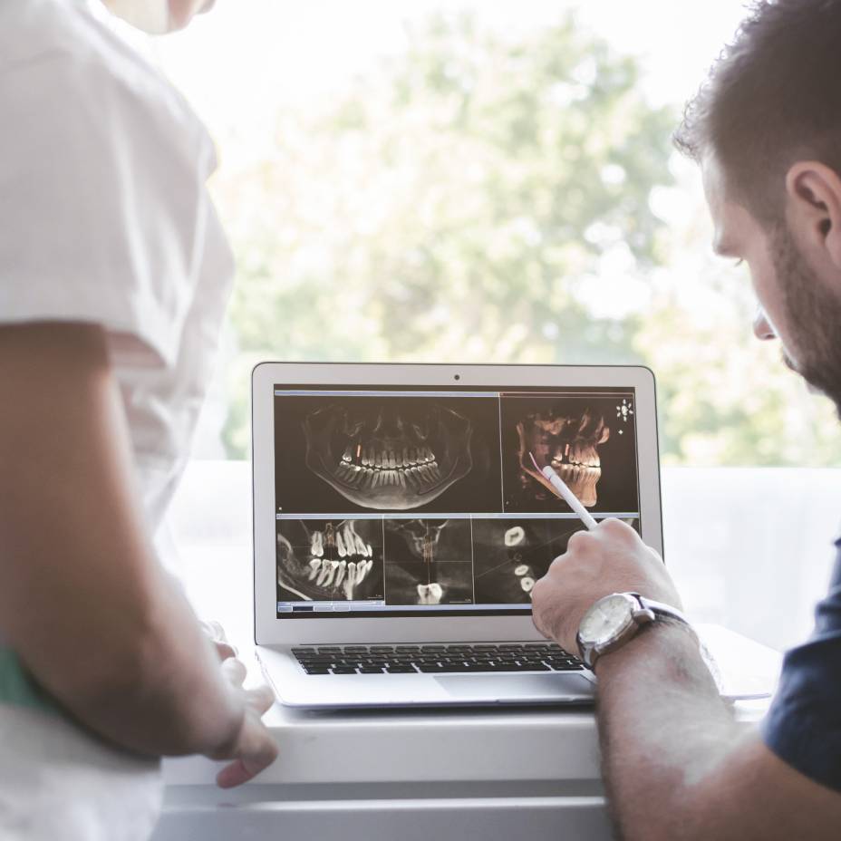 Zahnarzt zeigt Röntgenbilder auf dem Laptop