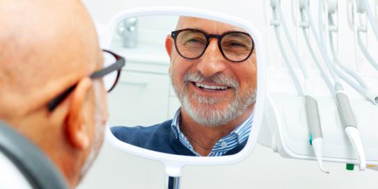Mann mit Handspiegel im zahnarztstuhl